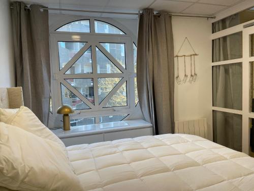 ein Schlafzimmer mit einem Bett und einem großen Fenster in der Unterkunft L'Eden in Vannes