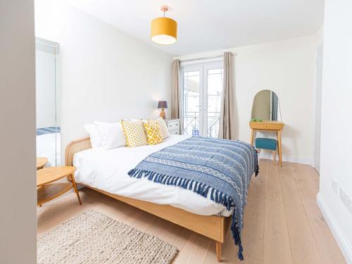 een witte slaapkamer met een bed met een blauwe deken bij 10 Tivoli Mews - By Luxury Apartments in Cheltenham