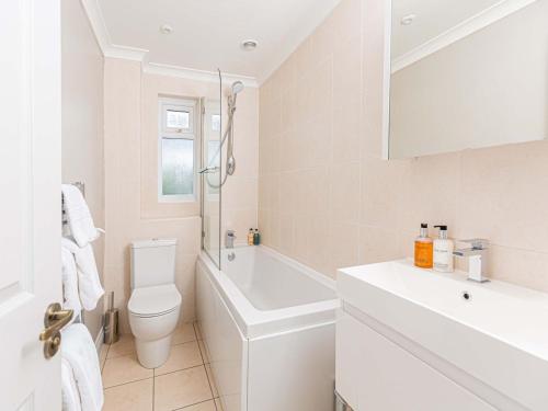 
a white bath tub sitting next to a white toilet at 10 Tivoli Mews - By Luxury Apartments in Cheltenham
