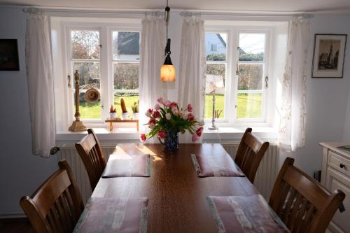 a dining room table with chairs and a vase of flowers at Haus-an-de-Marsch in Midlum