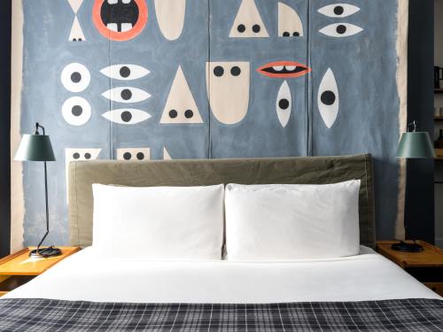 a bed with white pillows and a wall with eyes at Ace Hotel New York in New York