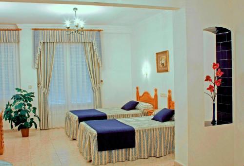 a bedroom with two beds with blue pillows at Hostal La Noria in Ruidera