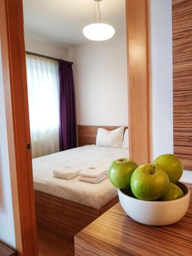 a bowl of apples on a table in a bedroom at Cosy one bedroom apartment, close to Iulius Mall in Cluj-Napoca