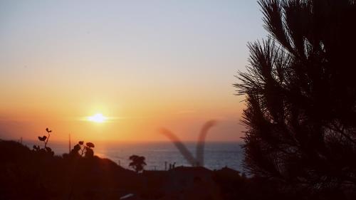 a sunset over the ocean with two people standing on a hill at Pension Galini in Armenistis