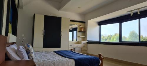 a bedroom with a bed and two large windows at The Periaheights in Periya
