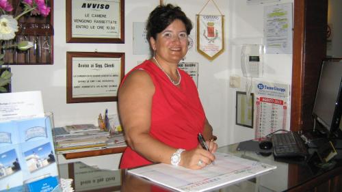 a woman in a red dress writing on a paper at Albergo Europa in Marina di Mancaversa