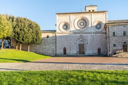 an old stone building with a grassy field in front at Hotel San Pietro in Assisi
