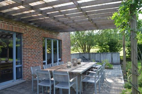 a patio with a table and chairs under a wooden pergola at Gîte Wellness "Le Poirier" in Durbuy