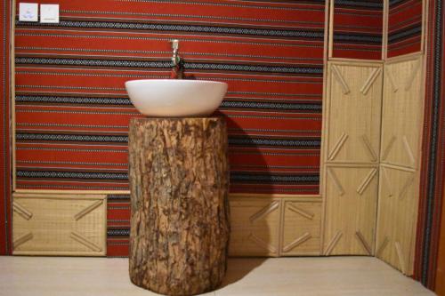 a bathroom with a white sink and a tree stump at Fort Guesthouse نُزل القلعة in Muscat