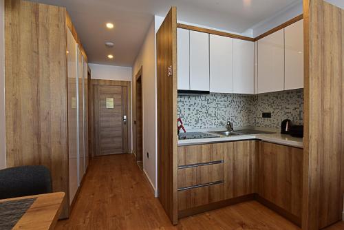 a kitchen with white cabinets and a wooden floor at Jasmin Elite Residence & SPA in Gümbet