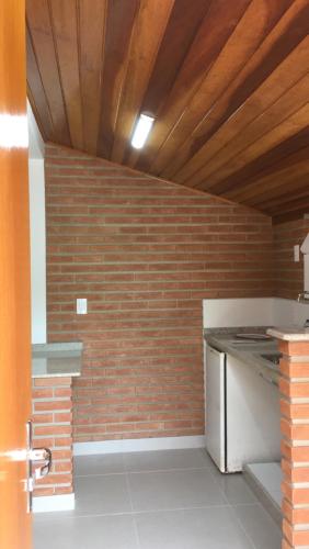 a kitchen with a brick wall and a stove at Vilarejo Penedo Chalés in Penedo
