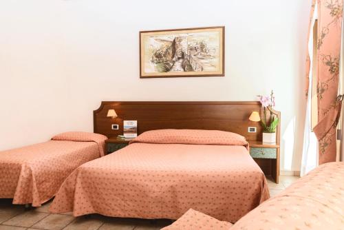 a bedroom with two beds and a picture on the wall at Hotel San Pietro in Assisi