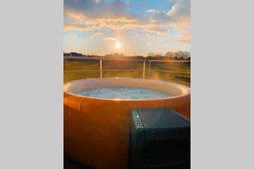 een hot tub met een televisie en de zonsondergang bij Le refuge des amoureux, charme et confort welness. in Vaux-sur-Sûre