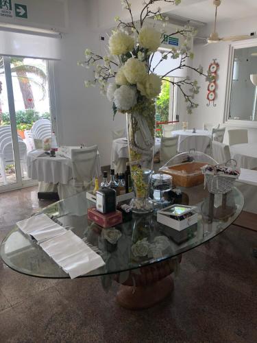 uma mesa de vidro com um vaso de flores em Piccolo hotel le Palme em San Bartolomeo al Mare