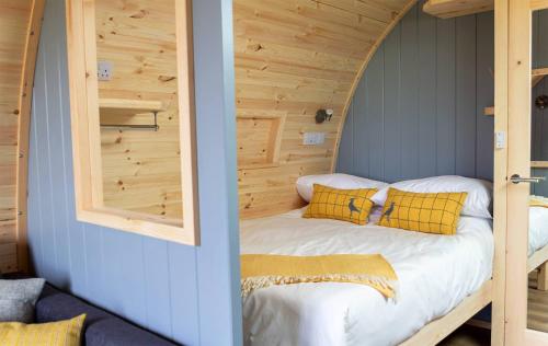 a bed in a room with a wooden wall at Air a’ Chroit Luxury Pods in Paible