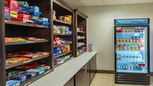 a store aisle with a refrigerator filled with food at Holiday Inn Express & Suites Houston South - Near Pearland by IHG in Houston