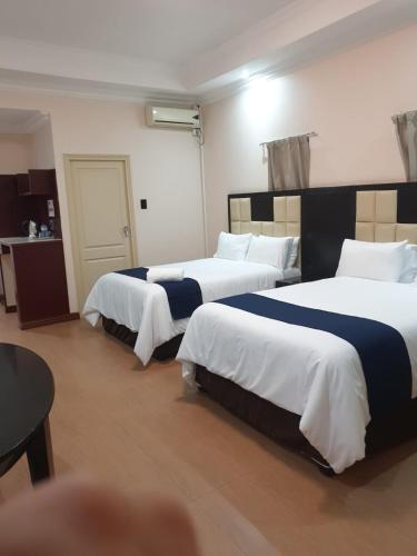 Habitación de hotel con 2 camas con sábanas blancas y azules en Al Hamra Hotel Durban, en Durban