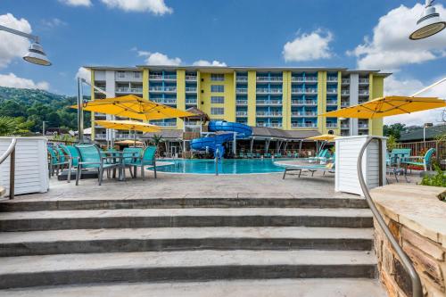 a hotel with a pool and tables and umbrellas at Margaritaville Resort Gatlinburg in Gatlinburg