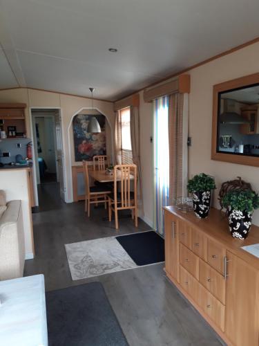 uma cozinha e sala de estar com mesa e cadeiras em Locatie Het Knooppunt Engelse Chalet em Nuis