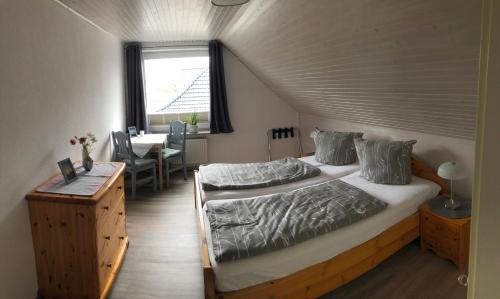 a bedroom with a bed and a table and a window at Haus Magnussen in Dagebüll