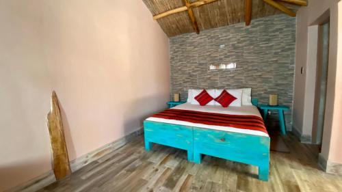 a bedroom with a blue bed with red pillows at Ickota B&B in San Pedro de Atacama