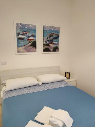 a bedroom with a blue bed with two pictures on the wall at Botteghelle Home in Casalnuovo di Napoli