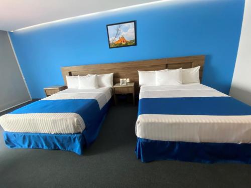 two beds in a hotel room with blue lighting at Wyndham Puebla Angelopolis in Puebla