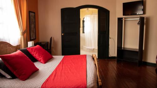 a bedroom with a bed with red pillows and a window at Hotel La Herreria Colonial in Popayan