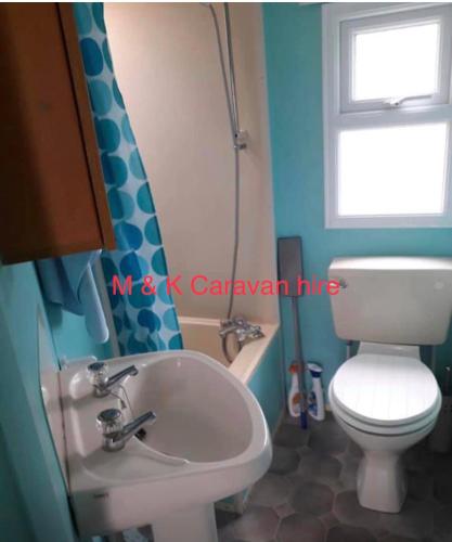 a bathroom with a sink and a toilet and a window at Beautiful 6 birth caravan in Ingoldmells
