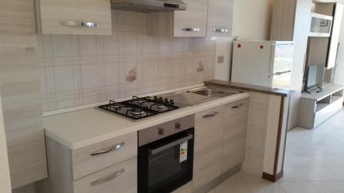 a white kitchen with a stove and a refrigerator at Casa Vacanze La Bandera 2 in Santa Teresa Gallura