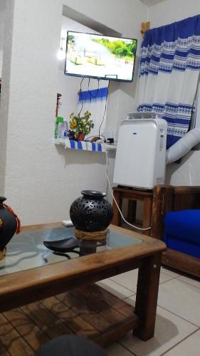 a living room with a table with a television and a table sidx sidx at Departamento la crucecita, con aire acondicionado, excelente ubicación, en segunda planta in Santa Cruz Huatulco