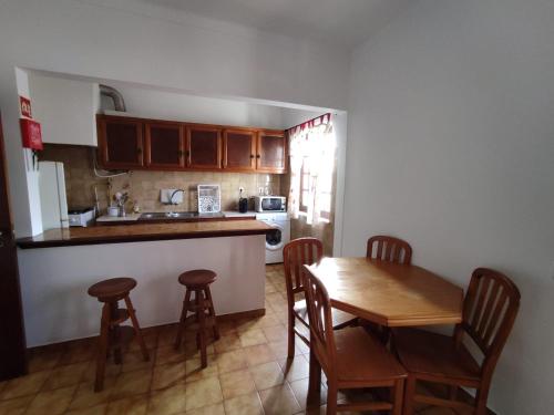 a kitchen with a wooden table and chairs and a kitchen with a sink at Apartamento Rosa in Porto Covo