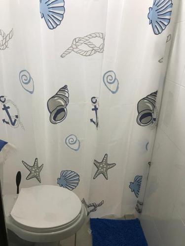 a bathroom with a toilet and a shower curtain with fish at Departamento la crucecita, con aire acondicionado, excelente ubicación, en segunda planta in Santa Cruz Huatulco