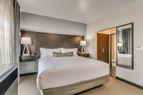 a hotel room with a large bed and two lamps at Staybridge Suites Lubbock South by IHG in Lubbock