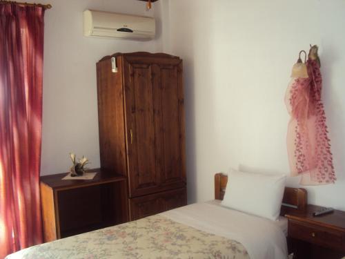 1 dormitorio con 1 cama y armario de madera en Vassilis Guesthouse, en Rapsáni