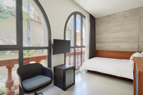 a bedroom with a bed and a chair and a desk at Sonder La Casa Del Sol in Barcelona
