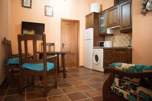 a small kitchen with a table and a refrigerator at Apartamentos Rurales Arco de Trajano in Alcántara