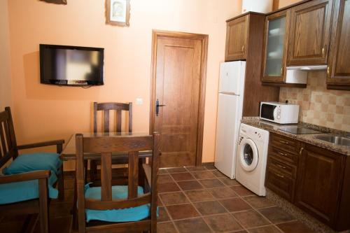 a small kitchen with a table and a refrigerator at Apartamentos Rurales Arco de Trajano in Alcántara