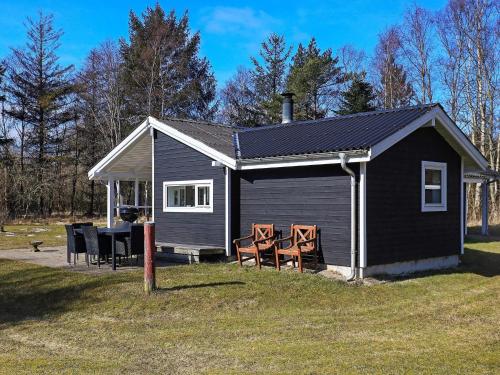 Ålbækにある5 person holiday home in lb kの小さな黒い家(椅子、テーブル付)