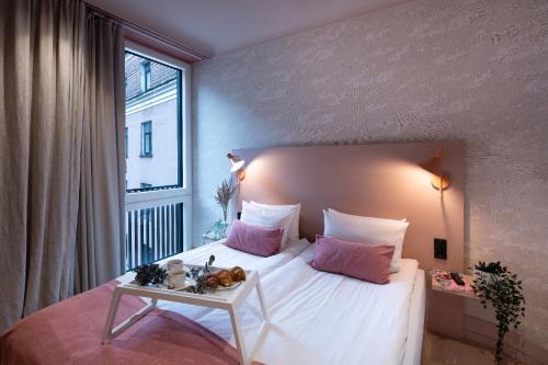 a bedroom with a white bed with pink pillows and a window at Redstone Apartments in Rīga
