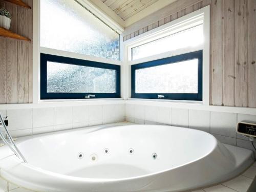 uma banheira branca numa casa de banho com 2 janelas em 8 person holiday home in Bindslev em Bindslev