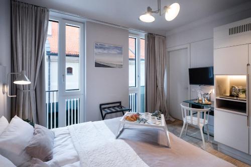 a bedroom with a white bed and a desk and some windows at Redstone Apartments in Rīga