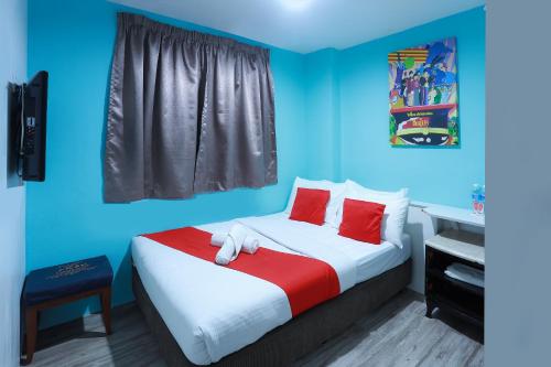 Schlafzimmer mit einem Bett mit roten Kissen und blauen Wänden in der Unterkunft Hotel Aman- Nilai & KLIA in Nilai