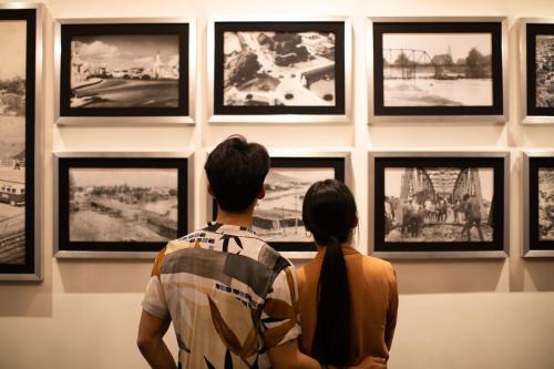 a man and a woman looking at a wall of pictures at The Bridge An Eclectic Luxotel in Chiang Mai