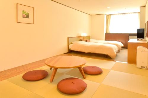a hotel room with two beds and a table at Hotel Kanronomori in Niseko