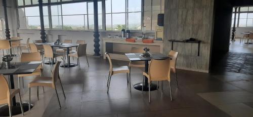a restaurant with tables and chairs in a room with windows at Nanutel Margao in Madgaon