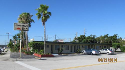 a street sign in front of a building with palm trees at Vacation Inn Motel in Fort Lauderdale