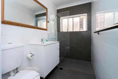 La salle de bains est pourvue de toilettes, d'un lavabo et d'un miroir. dans l'établissement Manly Beachfront Apartment, à Sydney