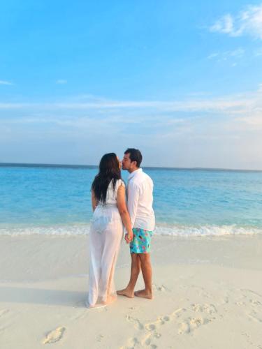 a man and a woman standing on a beach at Daisy Cottage Dhangethi in Dhangethi
