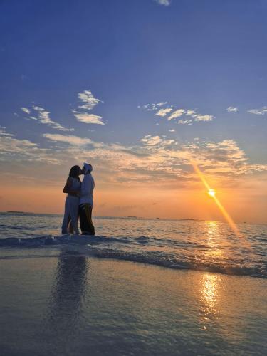 a couple standing on the beach watching the sunset at Daisy Cottage Dhangethi in Dhangethi